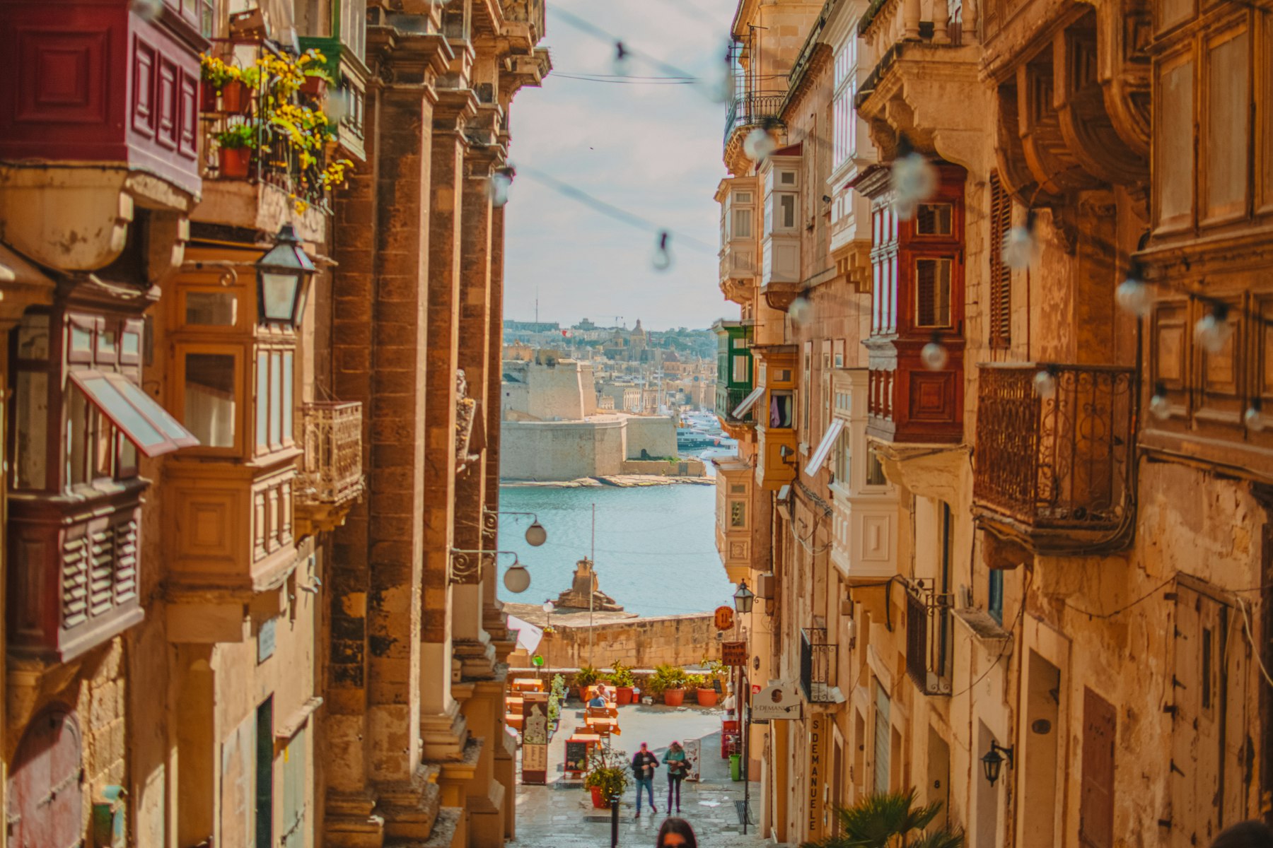 Straat in Valletta met houten balkons en zicht op de haven